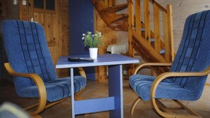 A cozy room with two blue upholstered chairs, a small table with a potted plant, and a wooden staircase. - Two-story Wooden Houses Close to the Beach (Mielno)