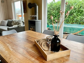 Une table de salle à manger en bois, sur laquelle sont posés un vase noir et un panier tressé.