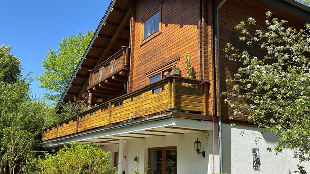 Ein zweistöckiges Holzhaus mit Balkon, Fenster und Tür.