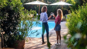 A wooden deck with a pool, surrounded by lush greenery and two umbrellas. - Bungalow Riva Degli Etruschi in San Vincenzo-formerly TUI Ferienhaus (San Vincenzo)