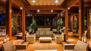 A spacious indoor area with wooden flooring, multiple seating arrangements, and large windows providing views of the outside. - Bungalow Riva Degli Etruschi in San Vincenzo-formerly TUI Ferienhaus (San Vincenzo)