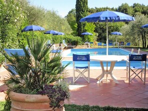 A poolside area with lounge chairs and umbrellas, a pool, and a sign reading 'La Scopa Montagne'.