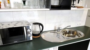 Una cocina con un tostador, un hervidor y un lavamanos de acero inoxidable.