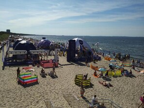 Une plage avec des tentes, des chaises de plage et des parasols.