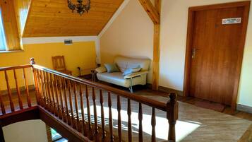 Una habitación con escalera de madera, un sofá, una puerta y una araña.