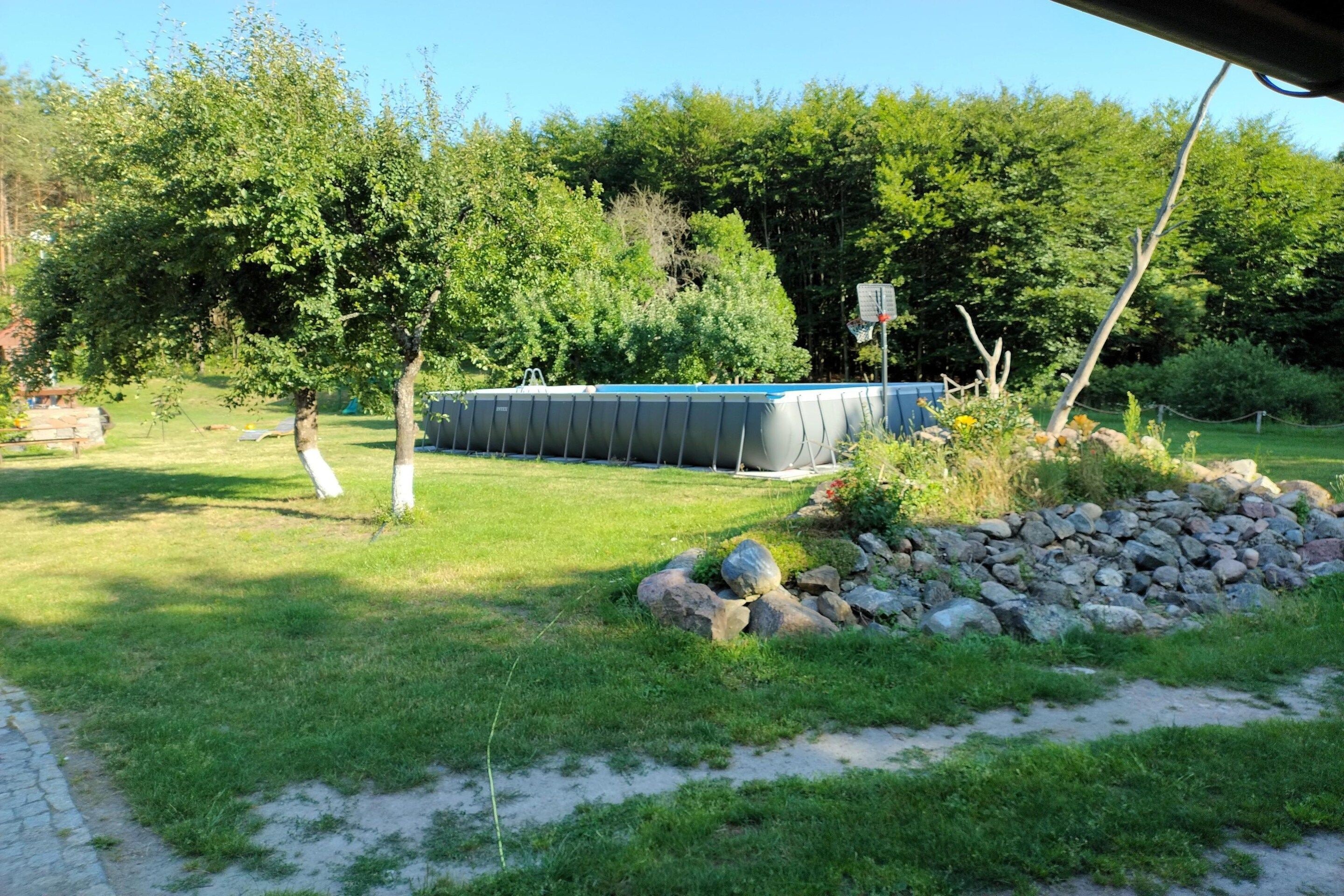 A backyard with a swimming pool, a stone wall, and a grassy area.