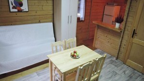 A small wooden dining table with four chairs, a bowl of fruit, and a whiteboard on the wall.