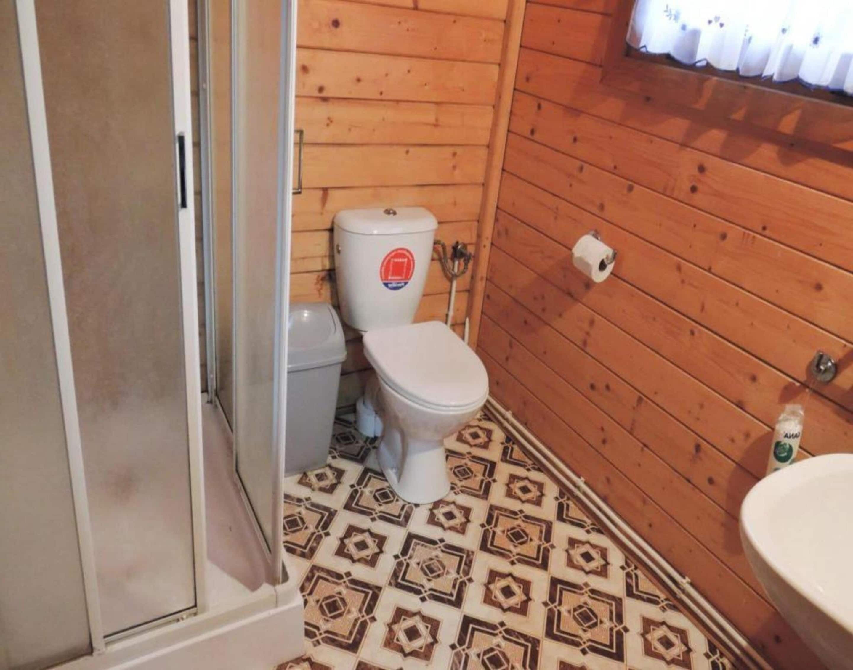 A small bathroom with a toilet, a sink, and patterned floor tiles.