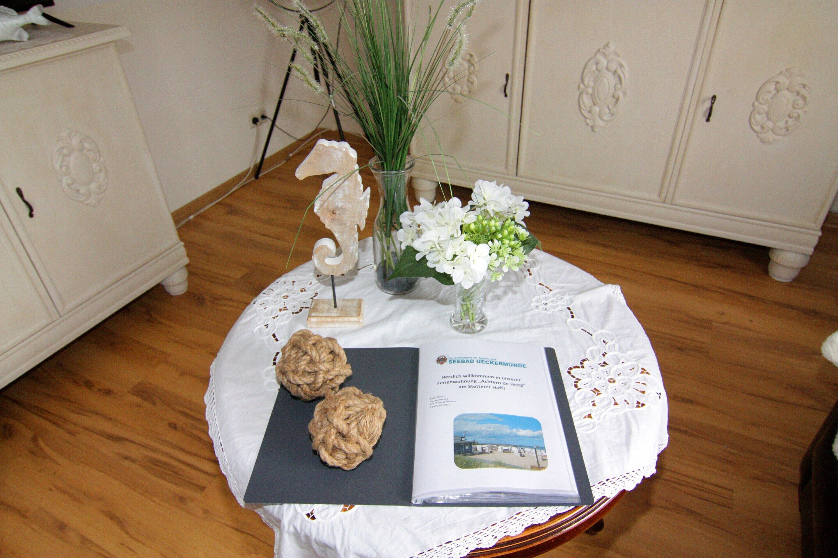 A table with a book, a vase with white flowers, and two decorative items.