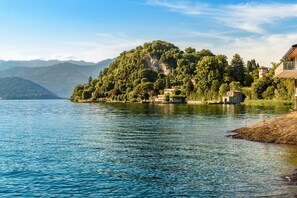 A lakeside view with a mountain in the background and a building with a balcony on the right. - Villa La Dolce Vita in Leggiuno (Leggiuno)