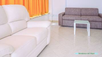 A living room with a white sofa, a brown sofa, and a small white table.