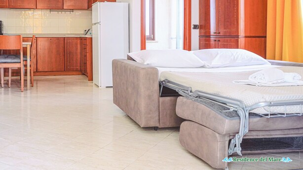 A compact room with a bed, a small kitchenette, and a dining area. - residence del mare (Ardea)