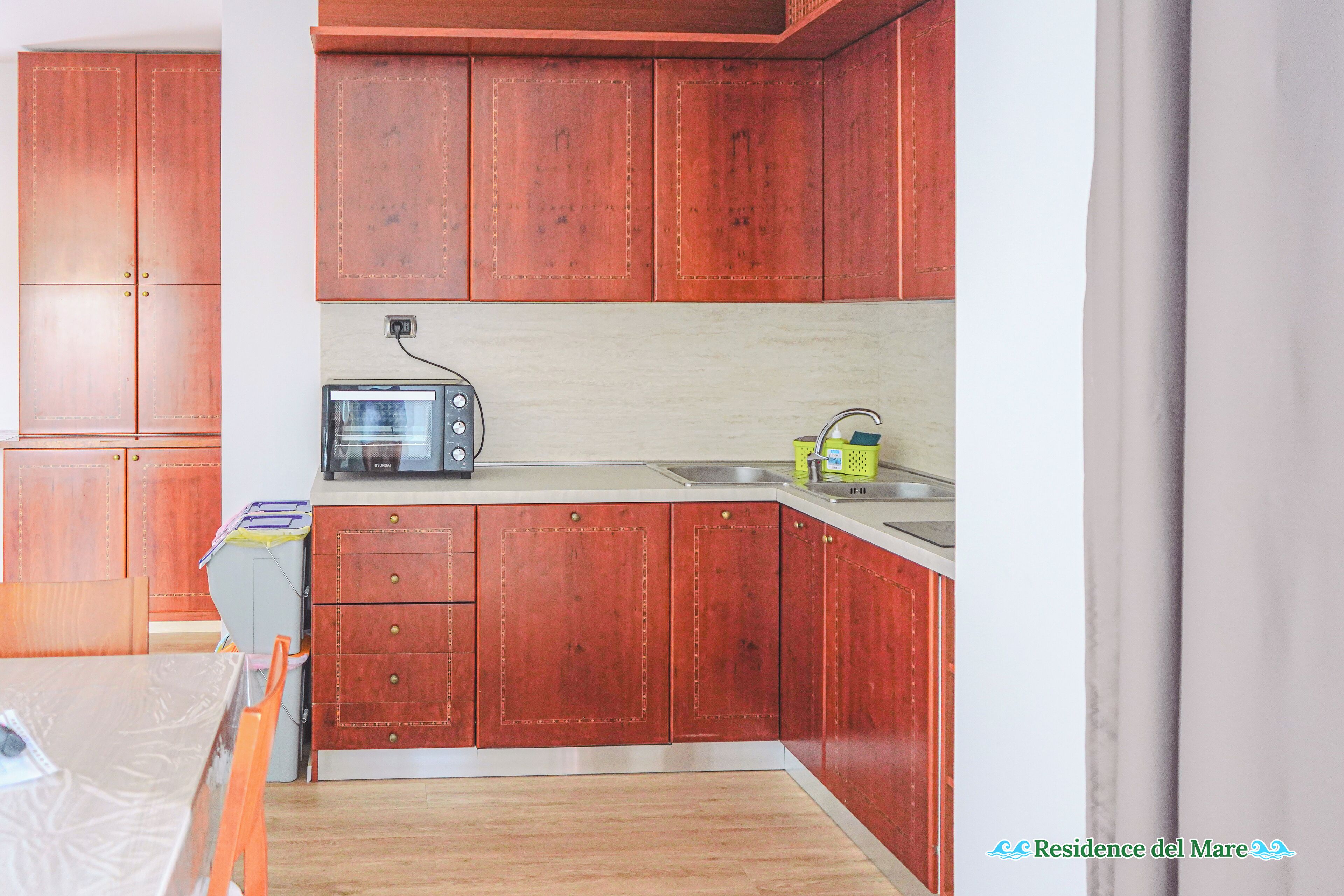 Une cuisine avec des meubles de rangement en bois, un four à micro-ondes et un évier.