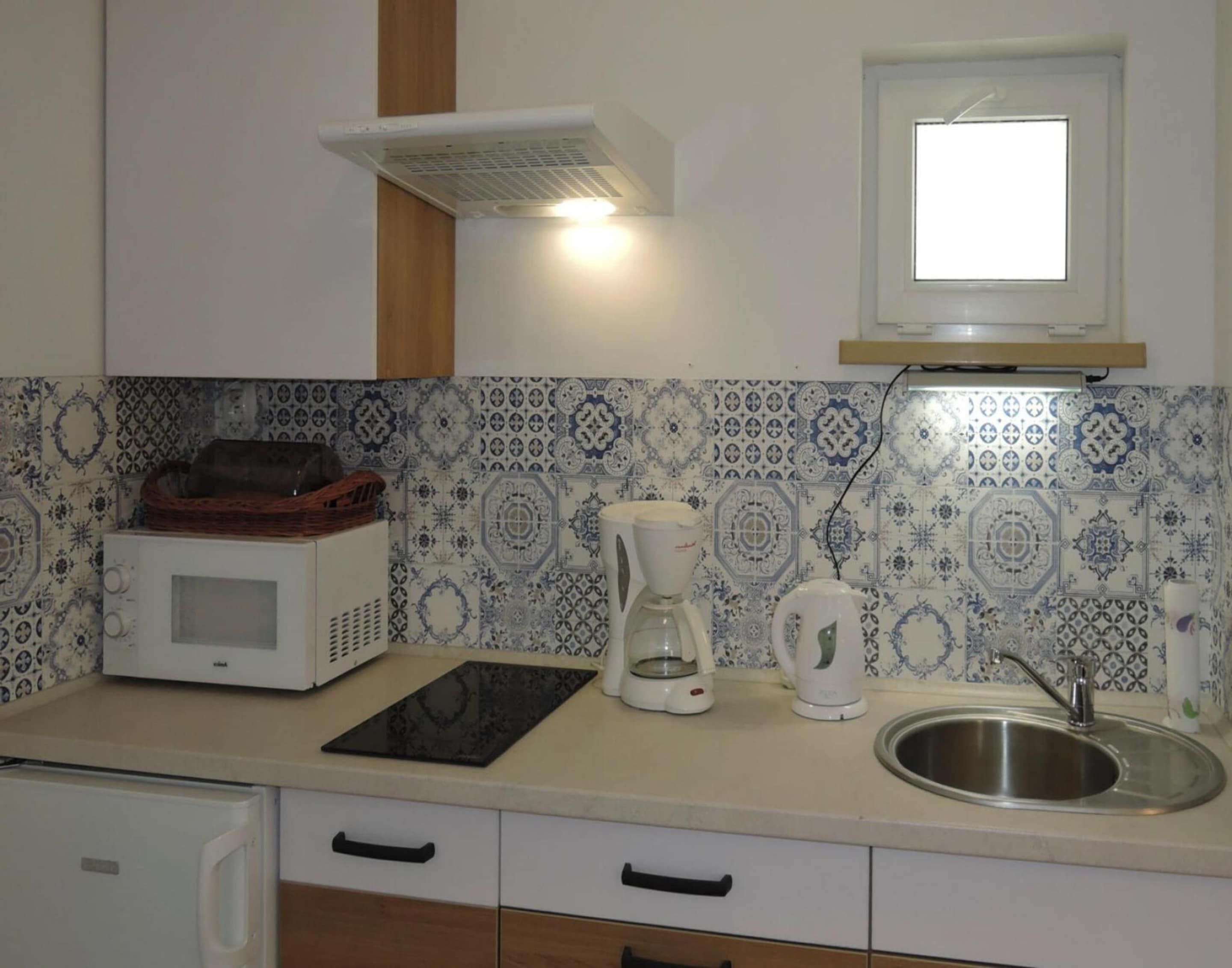A kitchen with a microwave, coffee maker, and a sink.