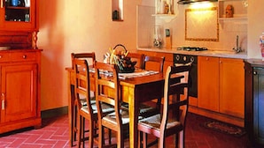 A kitchen with a wooden dining table, chairs, a brick arch, and a stove. - Apartment in Tuscany With Pool & Golf (Gambassi Terme)