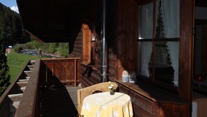A wooden cabin with a balcony, a table with a floral tablecloth, and a view of a mountain landscape. - Apartments Home Mario, See im Paznauntal (See)