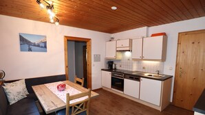 A cozy kitchen with wooden cabinets, a dining table with chairs, and a wooden ceiling. - Apartments Home Mario, See im Paznauntal (See)
