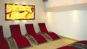 Une salle d’attente avec des chaises rouges et un grand tableau abstrait accroché au mur.