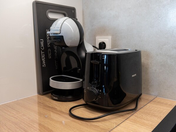 Une machine à café et un grille-pain sont posés sur un plan de travail en bois.