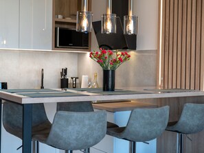 Une cuisine moderne dotée d’un îlot central, de tabourets de bar et de luminaires suspendus.