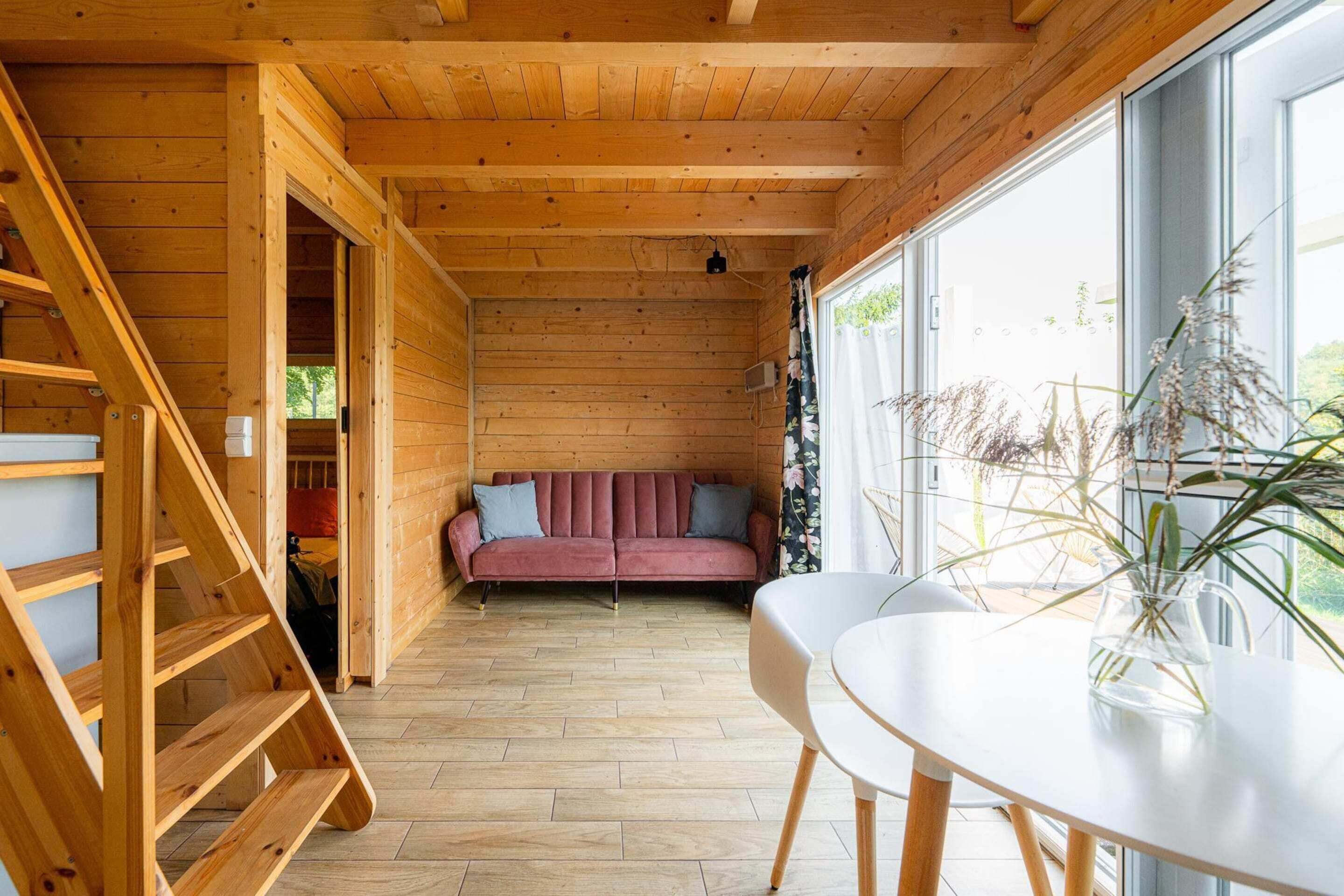 A wooden interior with a sofa, a table, and a staircase.
