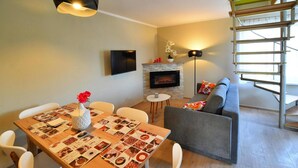 Un salon moderne avec une cheminée, une table à manger avec un set de table et un canapé gris.