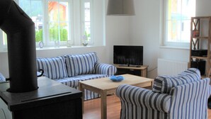 Una sala de estar con un sofá, sillones, una mesa de centro, televisión y chimenea.