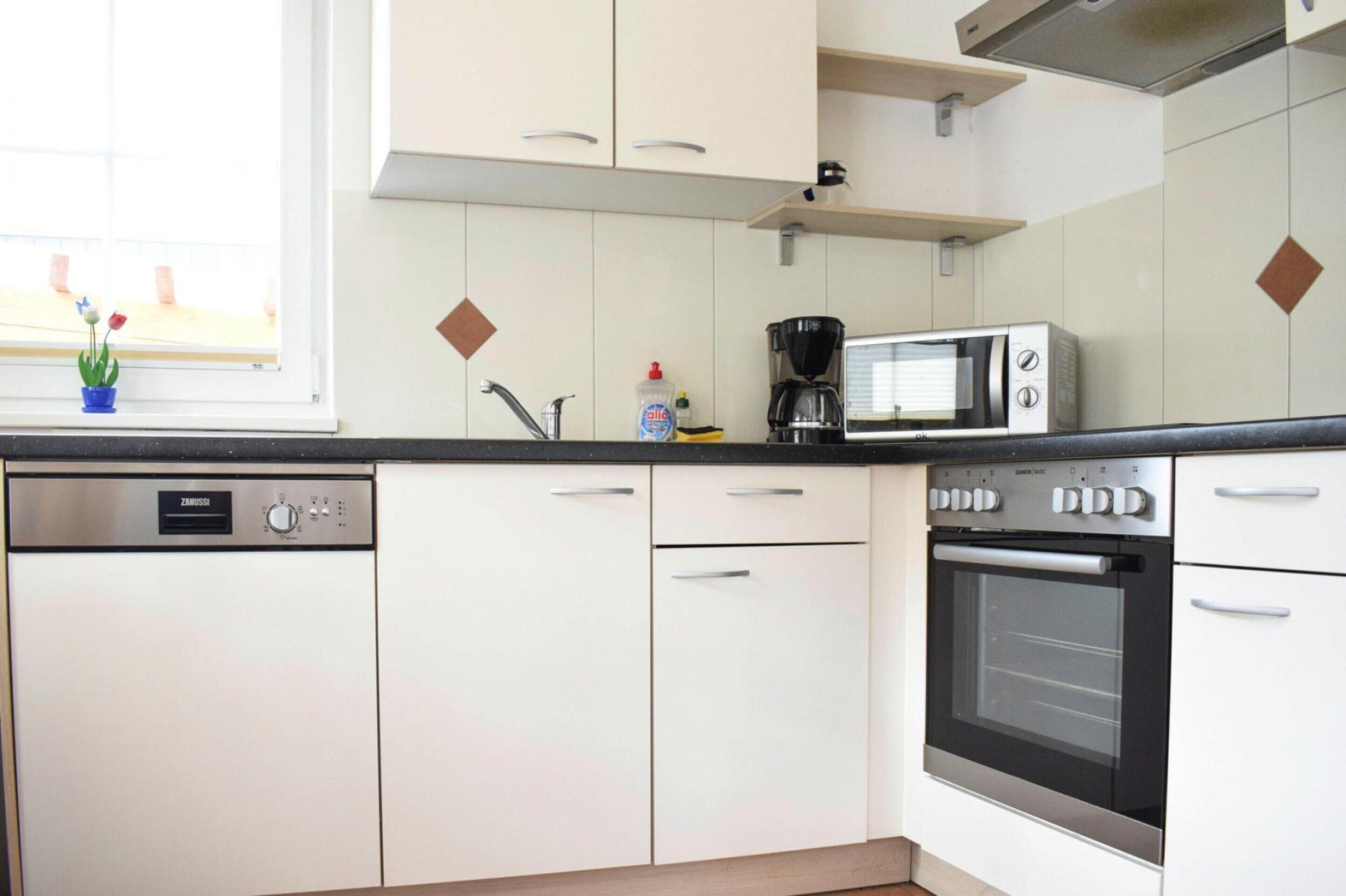 A modern kitchen with white cabinets, a dishwasher, a microwave, and an oven.