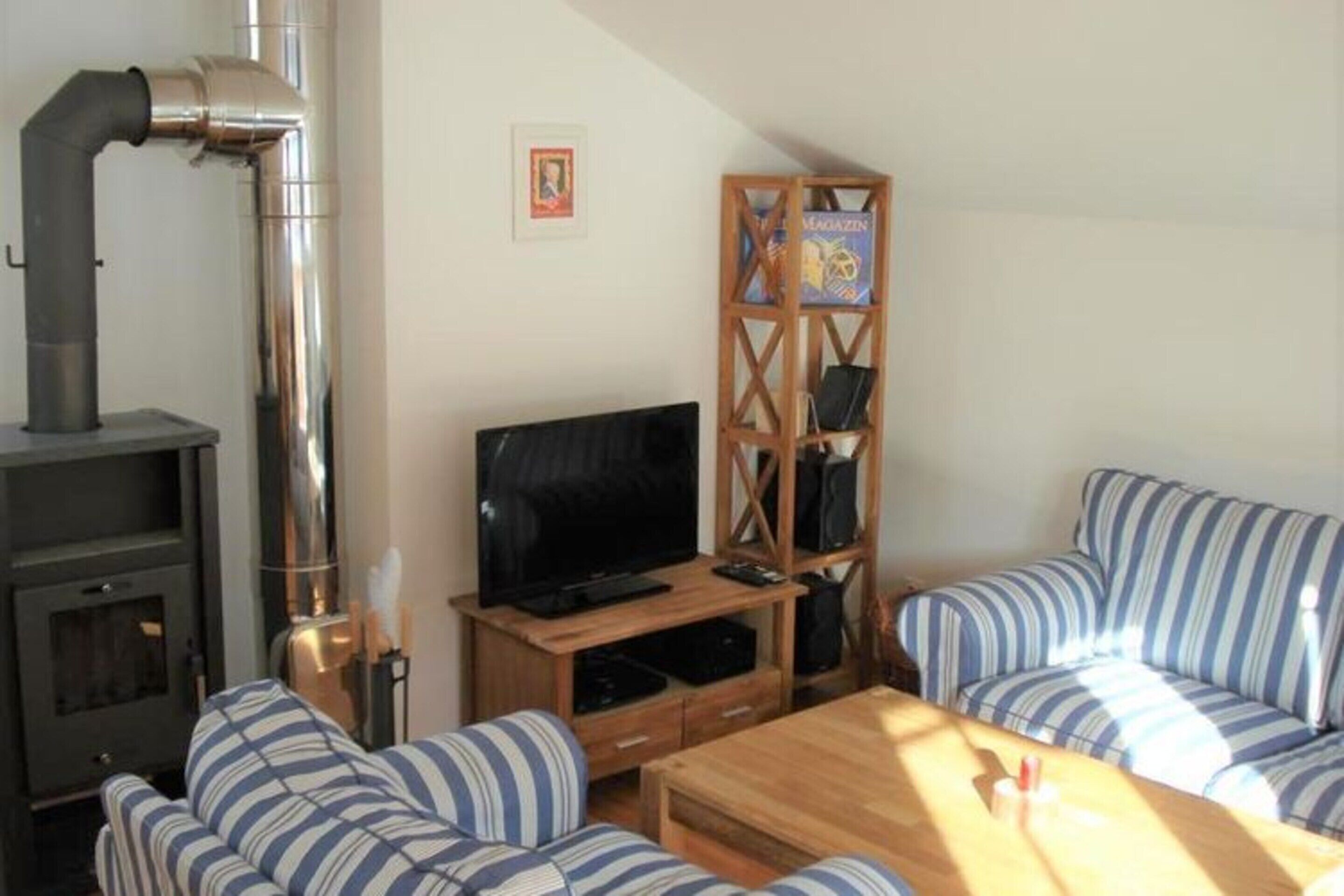 A cozy living room with a fireplace, a television, striped sofas, and a wooden coffee table.