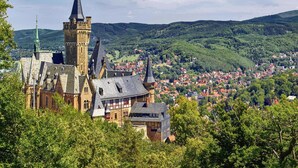 Un castello storico con numerose torri e una città sottostante.