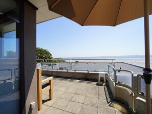 Ein Balkon mit Meerblick, ein Holzstuhl und ein Metallgeländer.