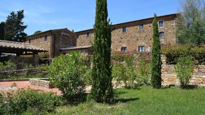 A stone building with a tiled roof, surrounded by greenery and a paved area. - Apartment in Campiglia Marittima (Campiglia Marittima)
