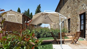 A stone building with a patio area featuring a table and chairs under a canopy. - Apartment in Campiglia Marittima (Campiglia Marittima)