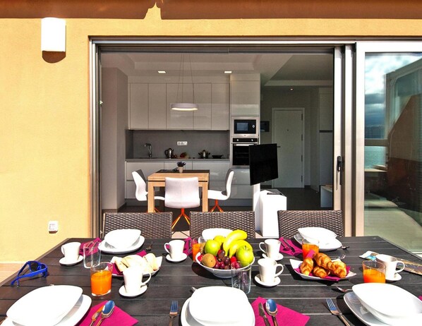 A breakfast table set with plates, cups, and a variety of food including fruits and pastries. - Apartment in Las Palmas de Gran Canaria (Las Palmas de Gran Canaria)
