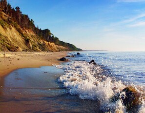 A beach with waves crashing onto the shore, a sandy beach, and a forested cliff in the background. - Single-story Holiday Home Near the Sea, Ustronie (Ustronie Morskie)