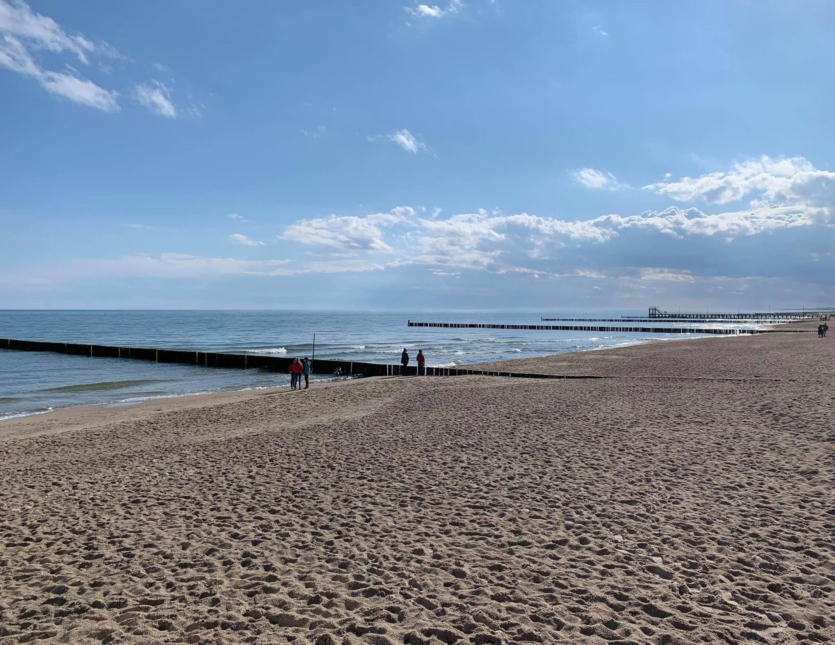 A wide sandy beach with a pier extending into the water.