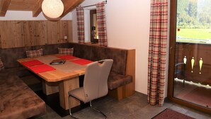 Un'accogliente zona pranzo con un tavolo di legno, sedute imbottite e tende a quadri.