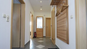 Un couloir avec des portes en bois, un extincteur et un sol carrelé.