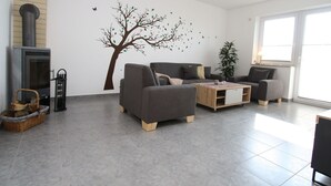Un salon moderne avec une cheminée, des canapés gris, une table basse et une grande fenêtre.