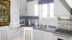 A kitchen with white cabinets, a microwave, a sink, and a stove. - Ferienwohnung in Oevenum auf Foehr (Oevenum)
