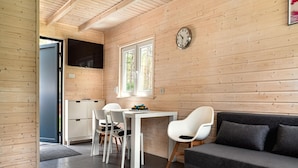 Ein modernes Interieur mit einer Holzwand, einem Essbereich mit Stühlen und einem Tisch, einer Couch und einem runden weißen Tisch.