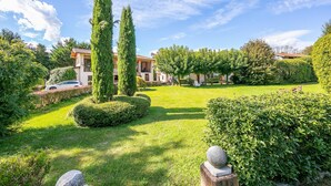 A well-maintained garden with neatly trimmed hedges, a stone pathway, and a traditional building with a tiled roof. - Timeless l Antico Mulino Della Bozza (Brebbia)