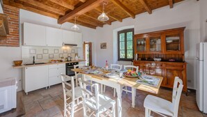 A kitchen with white cabinets, a wooden ceiling, and a dining table set for four. - Timeless l Antico Mulino Della Bozza (Brebbia)