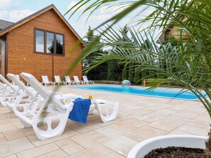A poolside area with lounge chairs and a wooden building in the background. - Comfortable Houses With Swimming Pools, Rewal (Rewal)