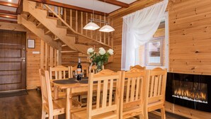 Ein Holzinterieur mit Esstisch, Stühlen, einer Treppe und einem Kamin.