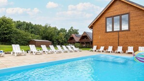 Ein Schwimmbad mit Liegestühlen, Holzhütten und blauem Himmel.