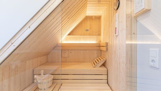 A sauna with wooden benches and a wooden bucket. - Moderne Doppelhaushalfte in Niebull (Niebuell)