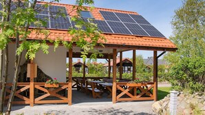 Ein hölzernes Gartenhaus mit Ziegeldach, Solaranlagen und Gartenmöbeln.