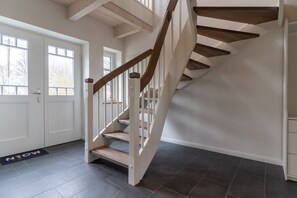 Un escalier avec des marches en bois et des rampes blanches menant à un palier.