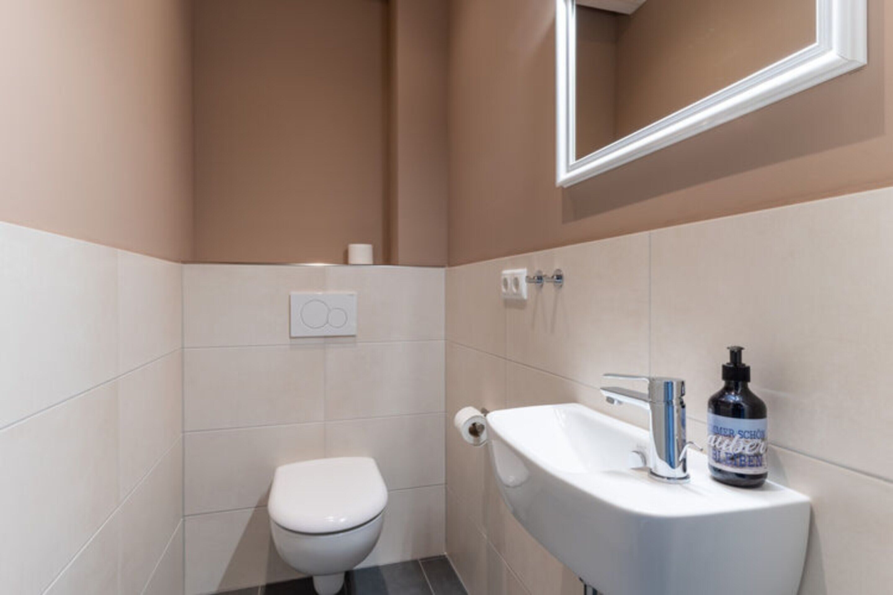 Ein kleines Badezimmer mit Toilette, Waschbecken und Spiegel.